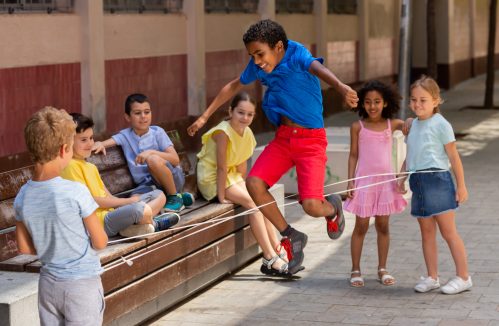 Crianças brincando de pular corda na quadra da escola.