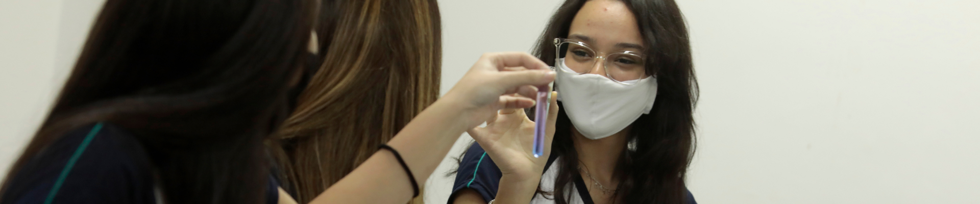 Alunas do Poliedro estudando com um tubo de ensaio na aula de química